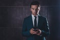 Young concentrated businessman chatting on smartphone on gray background