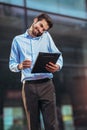 Young concentrated businessman walking outdoors on the street using mobile phone Royalty Free Stock Photo