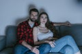 , concentrated couple watching tv on sofa