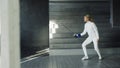 Young concentrated fencer woman practice fencing exercises and training for Olympic games competition in studio indoors