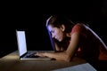 Young concentrated freelance worker or student woman working with computer laptop alone late at night in stress studying for exam Royalty Free Stock Photo