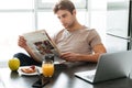 Young concentrated man reading newspaper while sitting in kitchen Royalty Free Stock Photo