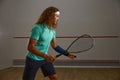 Young concentrated squash player practicing serve while exercising game at gym Royalty Free Stock Photo
