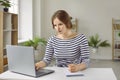 Young concentrated woman at home using laptop computer for remote work or online study. Royalty Free Stock Photo