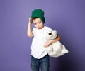 Young concerned kid boy child in green hat holding his polar bear toy. International day of polar bear concept Royalty Free Stock Photo