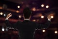 Young conductor with baton raised at a performance, rear view Royalty Free Stock Photo