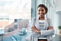 Young, confident and ambitious business woman or corporate professional standing arms crossed by an office window in the Royalty Free Stock Photo