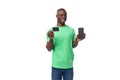 young confident american male advertiser dressed in green mockup t-shirt holding credit card and smartphone