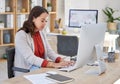 Young confident asian business woman sitting alone in an office and browsing the internet on a computer. Ambitious Royalty Free Stock Photo