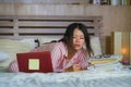 Young confident and beautiful Asian Korean student girl preparing University exam studying at home bedroom with laptop computer Royalty Free Stock Photo