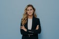 Young confident blonde business woman dressed in smart black costume standing with crossed arms Royalty Free Stock Photo