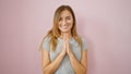 Young confident blonde woman joyfully smiles, standing casual with hands together, radiating positivity over an isolated pink Royalty Free Stock Photo