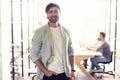 Young and confident businessman. Handsome young man smiling at camera while his colleagues working on background. Royalty Free Stock Photo