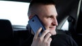 Young businessman talking on mobile phone while sitting on back seat of a car Royalty Free Stock Photo