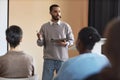 Young confident coach with tablet explaining point of presentation