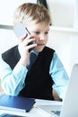 Young confident executive businessman boss boy in office talks on the phone sitting at the desk with laptop. Royalty Free Stock Photo