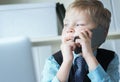 Young confident executive businessman boss boy in office talks on the phone sitting at the desk with laptop. Royalty Free Stock Photo