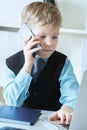 Young confident executive businessman boss boy in office talks on the phone sitting at the desk with laptop. Royalty Free Stock Photo