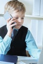 Young confident executive businessman boss boy in office talks on the phone sitting at the desk with laptop. Royalty Free Stock Photo