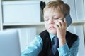 Young confident executive businessman boss boy in office talks on the phone sitting at the desk with laptop. Royalty Free Stock Photo