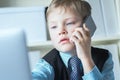 Young confident executive businessman boss boy in office talks on the phone sitting at the desk with laptop. Royalty Free Stock Photo