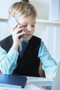 Young confident executive businessman boss boy in office talks on the phone sitting at the desk with laptop. Royalty Free Stock Photo