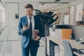 Young confident financier in formal suit with laptop and agenda, reading messages on smartphone Royalty Free Stock Photo