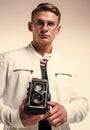 young confident guy in white urban clothes making photo with retro camera, fashion photographer Royalty Free Stock Photo