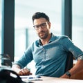 Young, confident and professional business man wearing glasses, sitting at his desk and working in a modern office Royalty Free Stock Photo