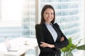 Young confident smiling businesswoman standing in office with ar Royalty Free Stock Photo