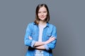 Young confident woman with crossed arms on gray background Royalty Free Stock Photo