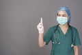 Young confident woman doctor in green scrubs is wearing surgical mask over grey background studio Royalty Free Stock Photo