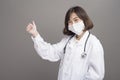 Young confident woman doctor is wearing surgical mask over grey background studio Royalty Free Stock Photo