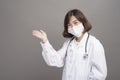 Young confident woman doctor is wearing surgical mask over grey background studio Royalty Free Stock Photo