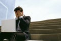 Young confidental businessman wearing suit and using modern laptop outdoors. Successful banker working outside during Royalty Free Stock Photo