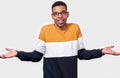 Young confused African American man shrugging with hands raised near shoulders smiling with sorry look as unaware or clueless. Royalty Free Stock Photo