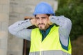 young construction worker covering ears