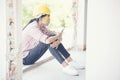 Young construction worker holding smart phone and sittin at construction site.Young Beautiful engineer working holding building Royalty Free Stock Photo