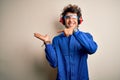 Young constructor man wearing uniform and earmuffs over isolated white background amazed and smiling to the camera while