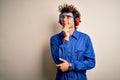 Young constructor man wearing uniform and earmuffs over isolated white background with hand on chin thinking about question,