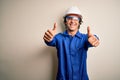 Young constructor man wearing uniform and security helmet over isolated white background approving doing positive gesture with Royalty Free Stock Photo