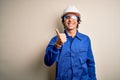 Young constructor man wearing uniform and security helmet over isolated white background doing happy thumbs up gesture with hand Royalty Free Stock Photo