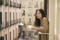 Young contemplative and beautiful Asian woman at home or hotel balcony - thoughtful Japanese girl having morning coffee enjoying