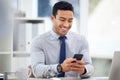 Young content mixed race businessman holding and using a phone sitting in an office at work. One hispanic male Royalty Free Stock Photo