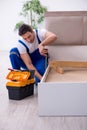 Young male contractor installing furniture at home