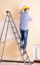 Young contractor sanding wall down with sandpaper