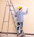 Young contractor sanding wall down with sandpaper