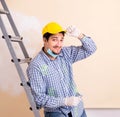 Young contractor sanding wall down with sandpaper