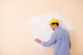 The young contractor sanding wall down with sandpaper