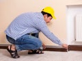 Young contractor sanding wall down with sandpaper